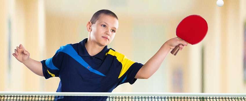 Young boy playing ping pong.